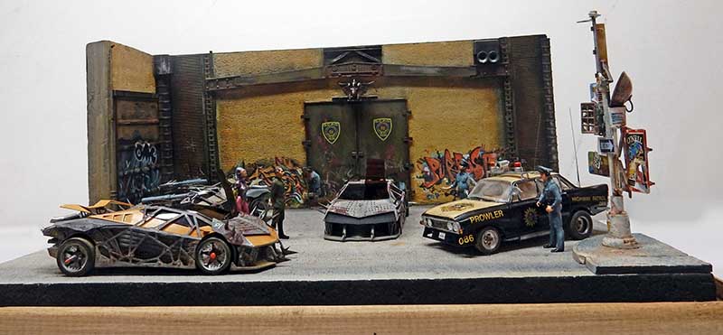 Diorama Future Cop avec voitures de police et bolide futuriste devant un mur couvert de graffitis