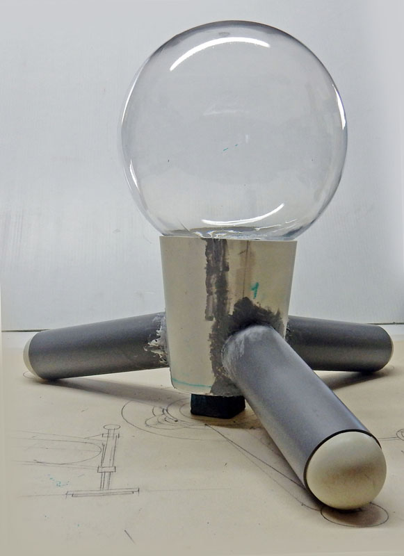 Maquette du G.N.U. avec sphère transparente sur socle cylindrique et bras métalliques, posée sur plan