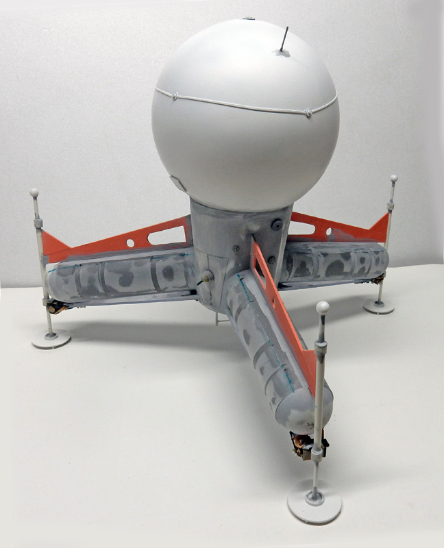 Maquette du G.N.U. à sphère blanche posée sur quatre pieds avec bras horizontaux gris et orange