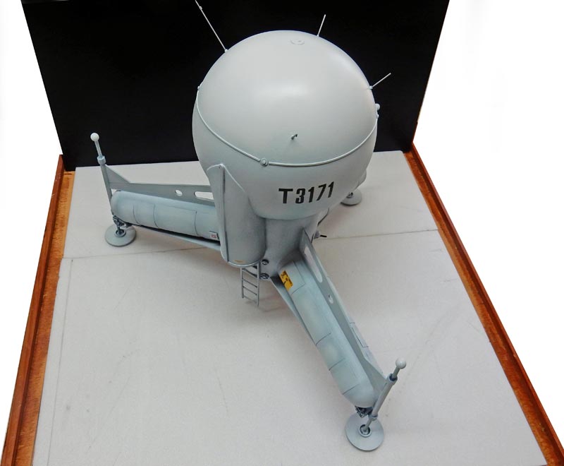 Maquette du G.N.U. sphérique gris immatriculé T3171 sur trois pieds, posée sur diorama