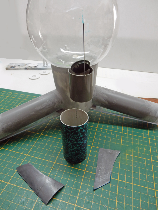 Maquette en construction du vaisseau G.N.U. avec sphère transparente et coque sur tapis de découpe