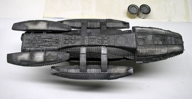 Maquette du Battlestar Galactica vue de dessus avec deux pots de peinture à côté