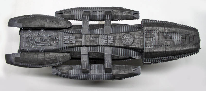 Maquette du vaisseau Battlestar Galactica peinte en gris vue de dessus sur fond blanc