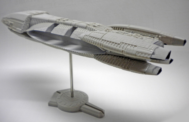 Maquette non peinte du vaisseau Galactica sur son socle, vue de profil