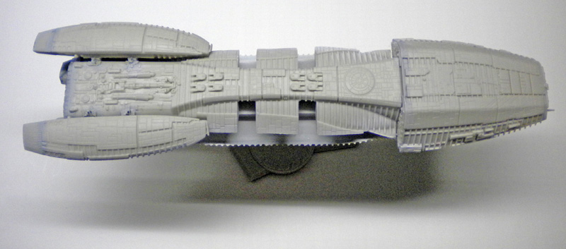 Maquette du vaisseau Battlestar Galactica en gris, vue de profil, non peinte avec détails de surface gravés