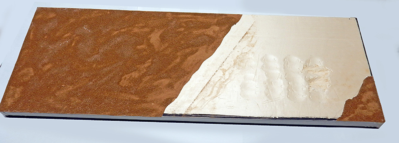 Socle du décor en cours de préparation, terre ocre appliquée sur une planche de bois