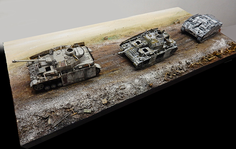 Diorama de trois chars allemands aux teintes hivernales sur un terrain enneigé et boueux jonché de débris