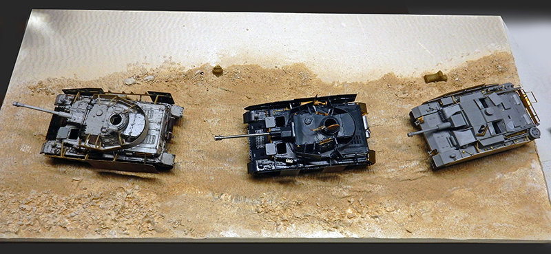 Trois maquettes de chars allemands à différents stades de peinture sur un diorama de terrain