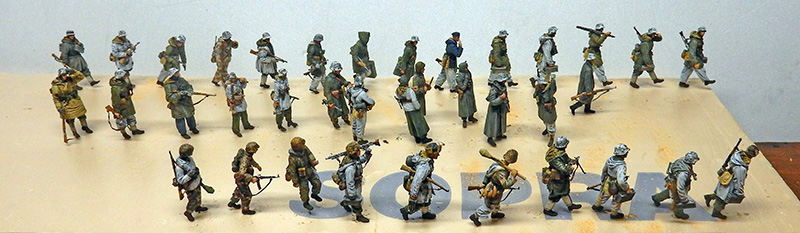 Nombreuses figurines de soldats peintes en tenues hivernales grises disposées sur un socle clair