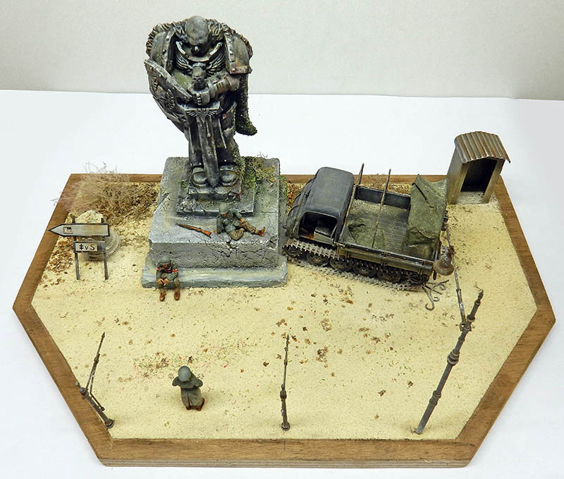 Diorama en cours de mise en peinture : statue, semi-chenillé, guérite et soldats sur socle hexagonal