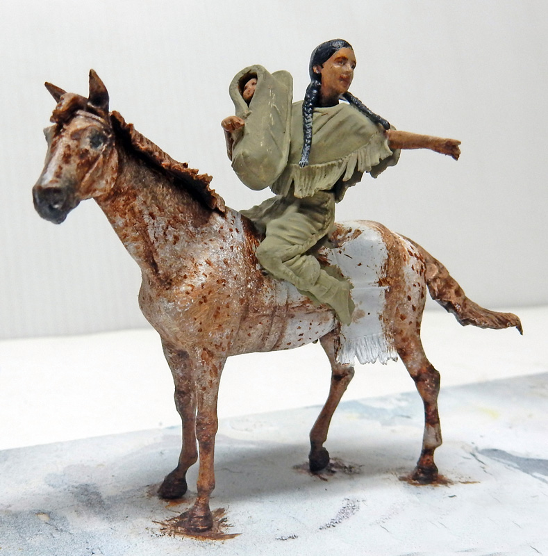 Figurine peinte d'une femme indienne portant un bébé, à cheval sur un appaloosa