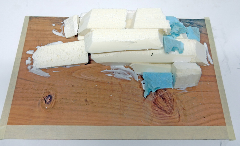 Blocs de mousse blanche et bleue collés sur une planche de bois pour maquette
