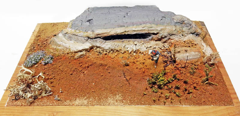 Diorama de maquettisme représentant un paysage désertique rocheux avec végétation et figurine sur socle en bois