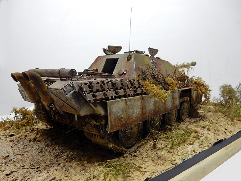 Maquette de Jagdpanther en camouflage vieilli sur diorama sablonneux avec végétation et chenilles de rechange