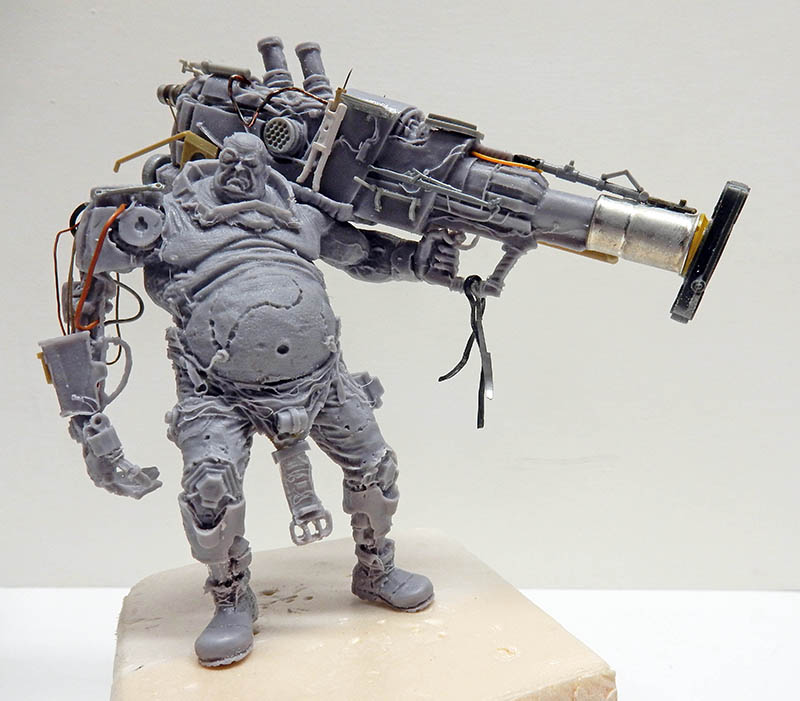 Figurine cyborg obèse non peinte portant un énorme canon mécanique sur l'épaule droite