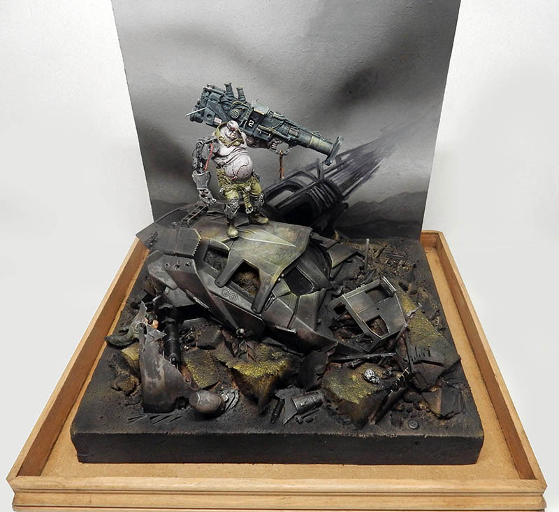Diorama de figurine cyborg armée debout sur un véhicule détruit parmi des débris