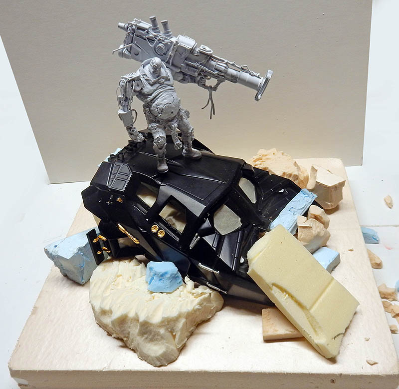 Figurine cyborg gris avec énorme canon debout sur un véhicule noir, diorama en construction