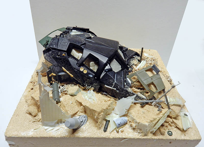 Maquette de véhicule blindé noir émergeant d'un sol détruit avec débris épars
