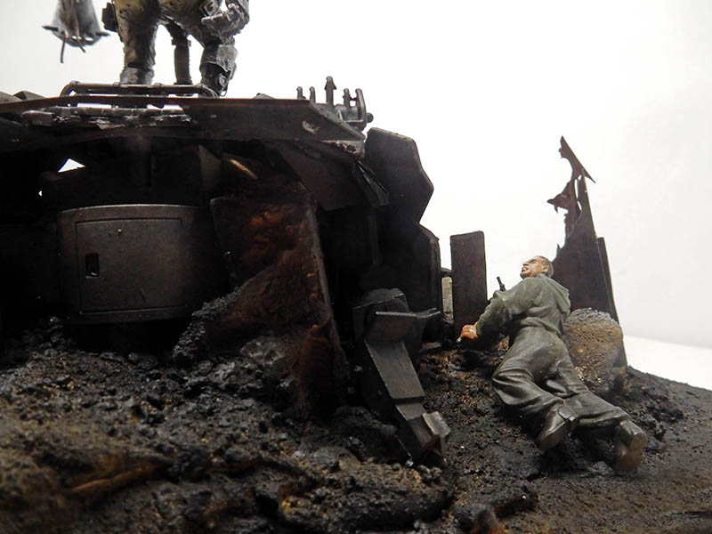 Diorama de maquette montrant un soldat blessé au sol près d'un véhicule blindé détruit sur terrain calciné