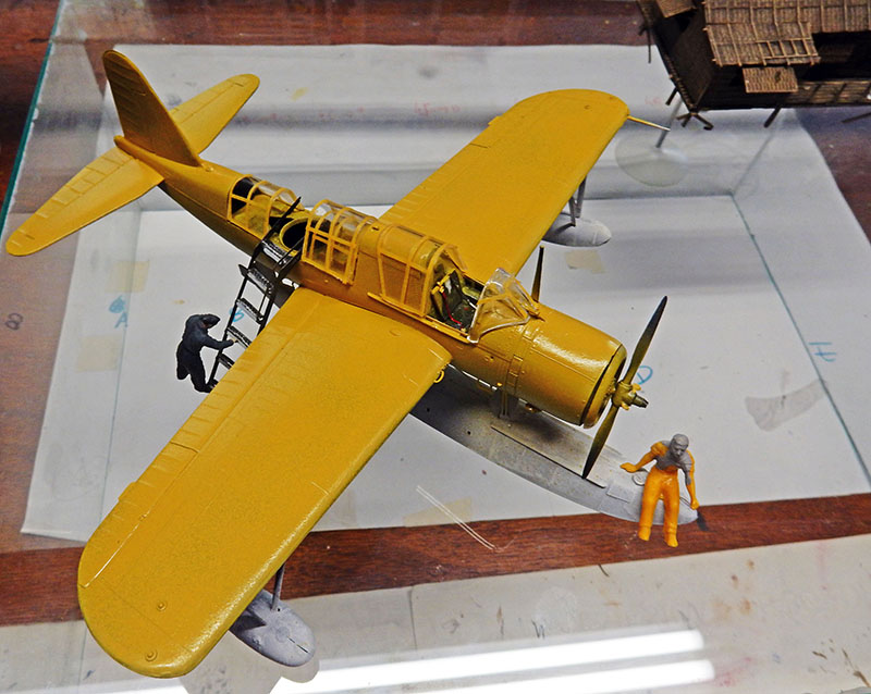Maquette du Vought OS2U Kingfisher jaune sur flotteur avec figurines et échelle d'accès au cockpit