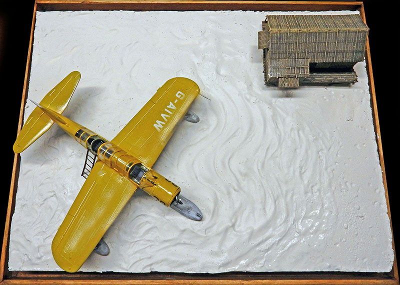 Maquette d'hydravion Vought OS2U Kingfisher jaune sur diorama d'eau avec hangar