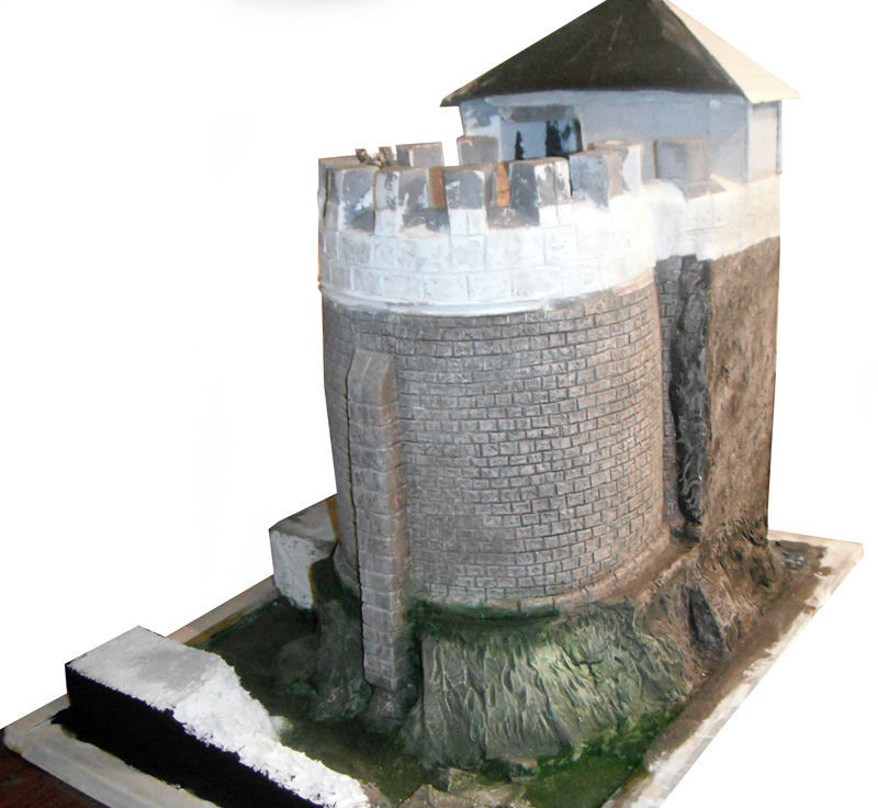 Maquette d'un donjon médiéval en pierre avec tour ronde crénelée et toiture