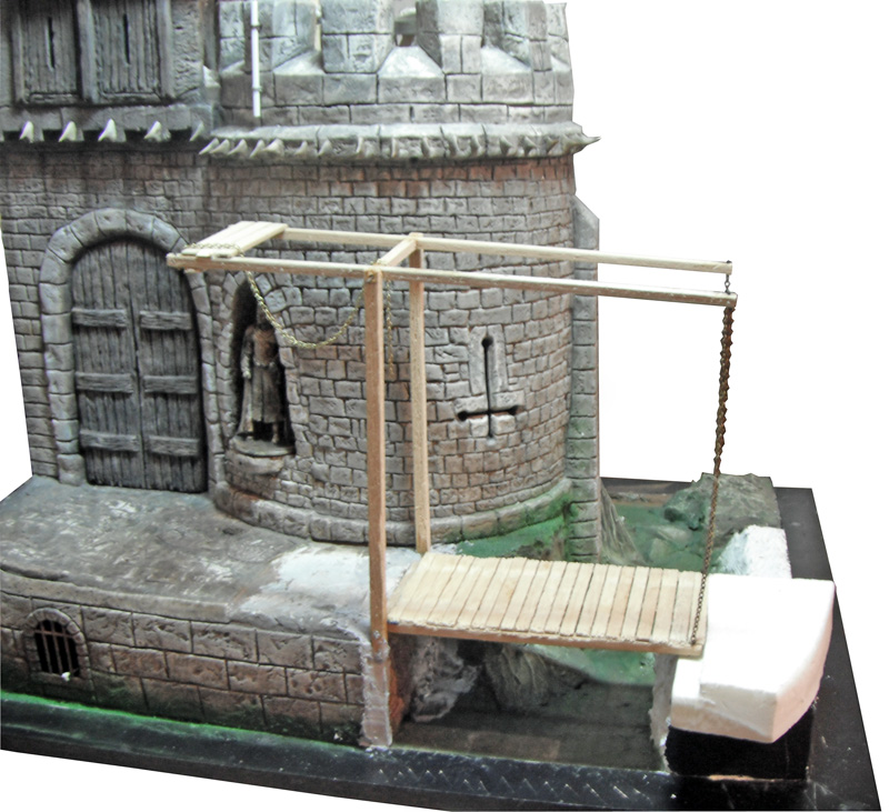 Maquette d'un donjon médiéval en pierre avec pont-levis en bois et porte cloutée