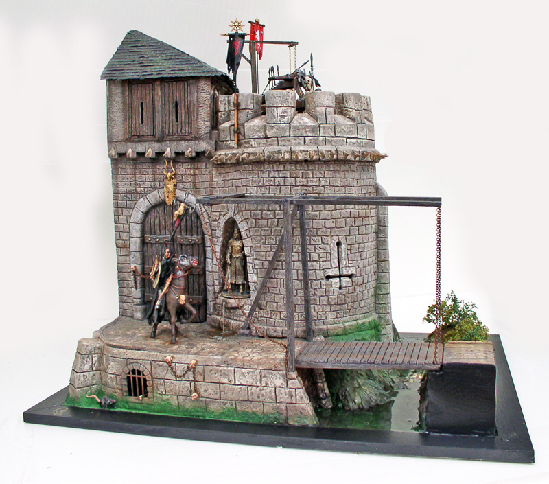 Maquette de donjon médiéval en pierre avec cavalier, pont-levis, bannières rouges et catapulte sur le toit