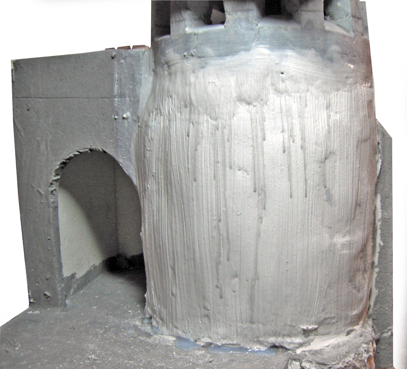 Maquette de donjon cylindrique enduit de mastic gris près d'une porte voûtée
