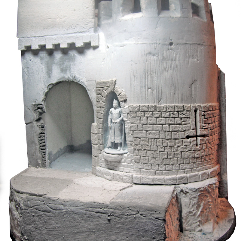 Maquette de donjon médiéval avec tour crénelée et statue de chevalier dans une niche