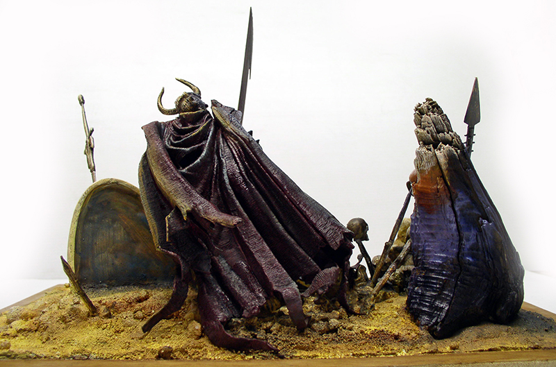 Diorama de figurine encapuchonnée à cornes drapée d'une longue cape parmi lances et débris