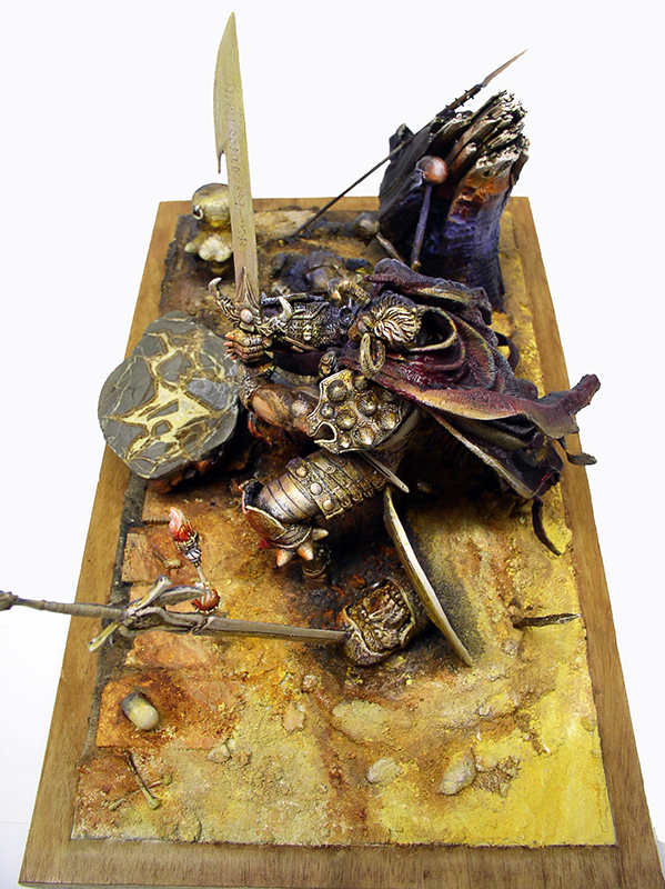 Diorama de figurine peinte représentant un guerrier en armure dorée brandissant une épée sur un socle