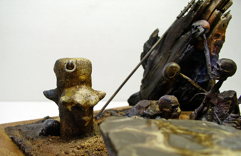 Diorama de maquettisme montrant des squelettes près d'une épave en bois et une borne rouillée