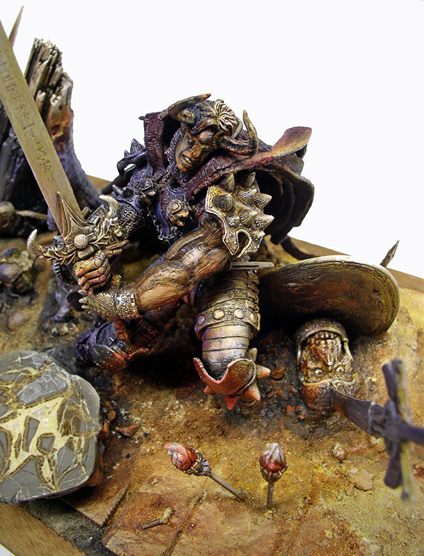 Figurine peinte d'un guerrier en armure brandissant une épée sur un diorama rocheux