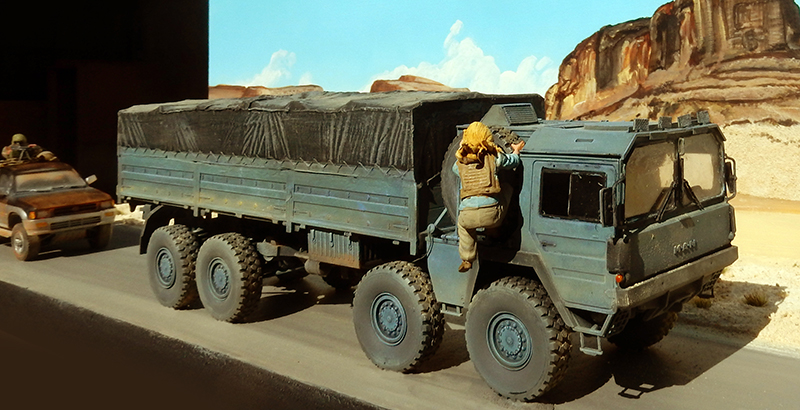 Maquette de camion militaire bâché avec figurine sur fond de désert rocheux