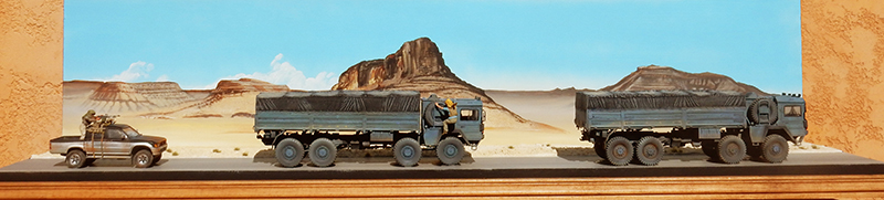 Diorama de deux camions militaires bleus et un pick-up dans un paysage désertique montagneux