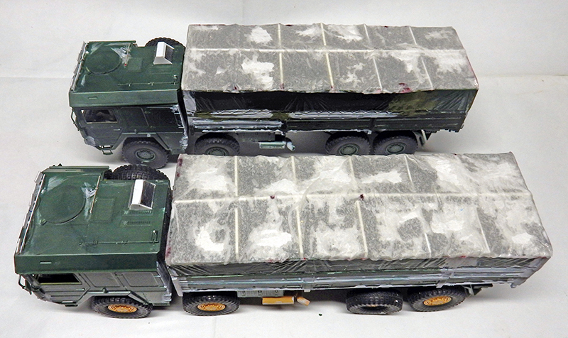 Deux maquettes de camions militaires bâchés verts vus de dessus sur fond blanc