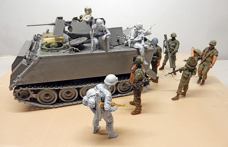 Maquette du M113 A1 ACAV entouré de figurines de soldats, certaines peintes d'autres en gris