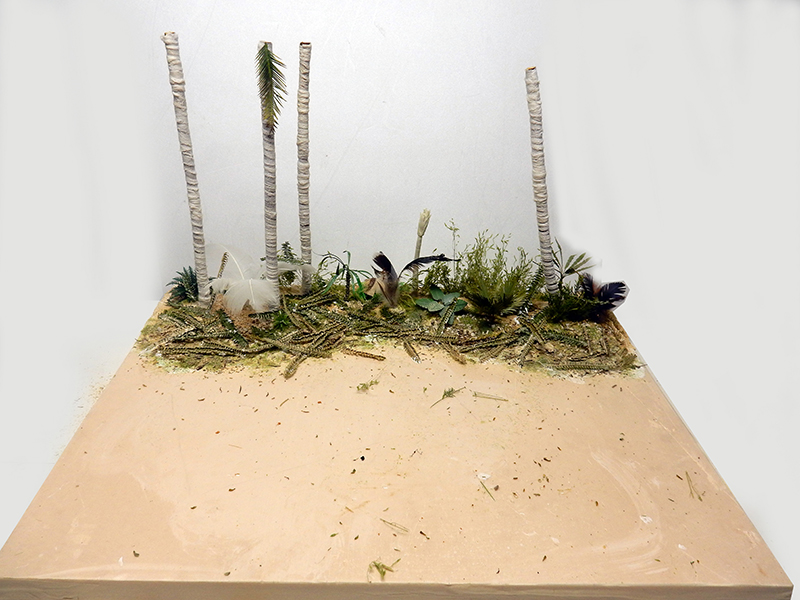 Diorama en construction avec troncs de palmiers, végétation tropicale et sol sableux pour maquette M113