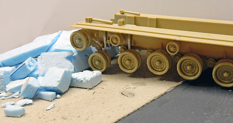 Châssis du M88A1 sans peinture posé sur un décor en construction avec gravats de mousse bleue