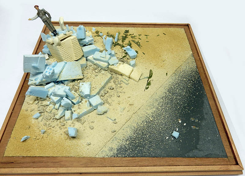 Base de scène en cours : sable, gravats de ruines, route goudronnée et figurine