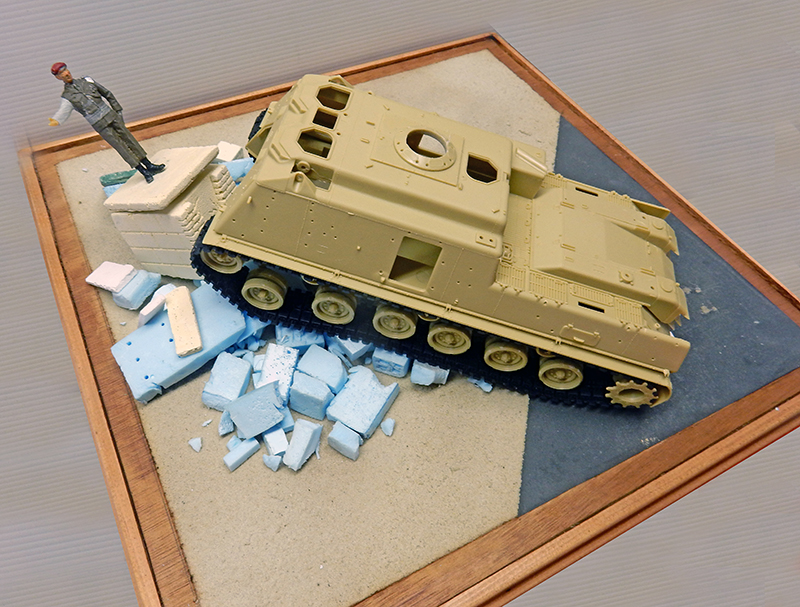 Maquette M88A1 beige posée sur base en cours d'aménagement avec gravats et figurine