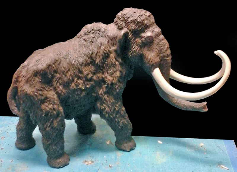 Maquette de mammouth laineux brun aux longues défenses ivoire sur fond noir