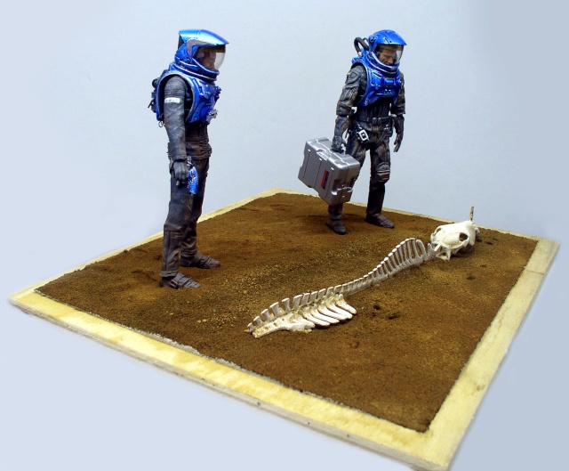 Diorama de deux astronautes en combinaison bleue découvrant un squelette sur sol martien