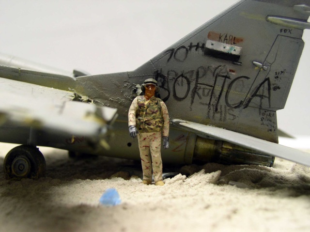 Figurine de soldat en treillis désert posée près de l'épave d'un Mig 29 couverte de graffitis