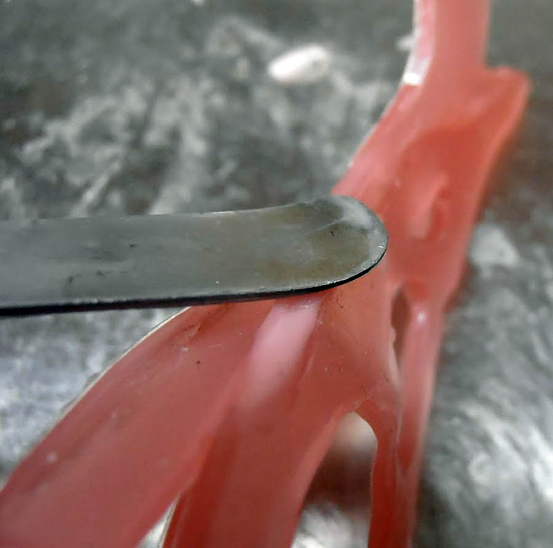 Gros plan sur une spatule lissant la mâchoire du crâne en pâte rose