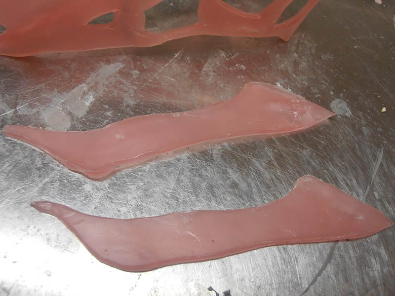 Deux longues pièces de mâchoire en pâte à modeler rose posées sur un plan de travail métallique