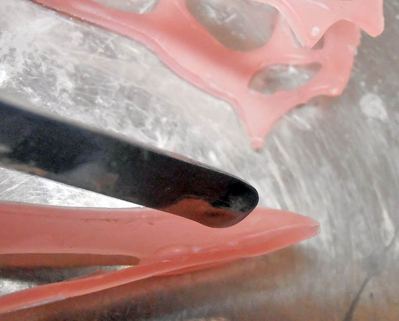 Gros plan sur le creusement d'une ouverture du crâne en pâte rose avec gouge