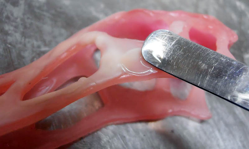 Gros plan sur le lissage à la spatule métallique du crâne en pâte rose