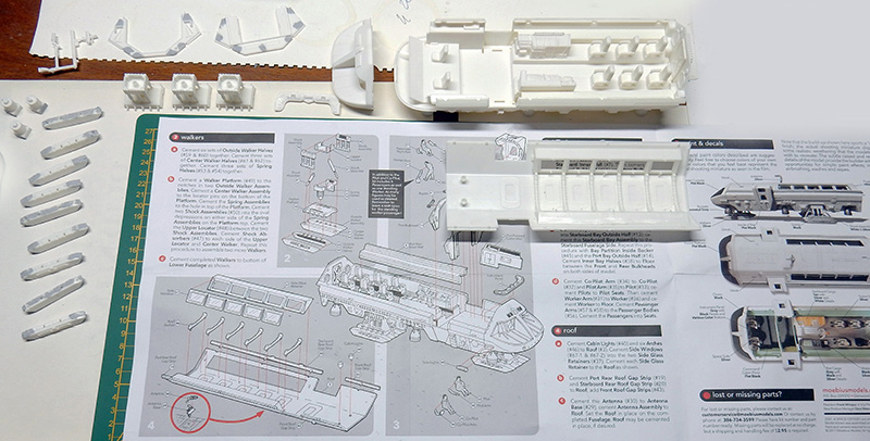 Pièces blanches non assemblées de la maquette Moonbus posées sur la notice de montage